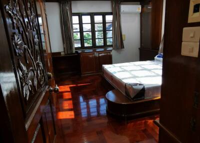 Wood-paneled bedroom with large window and polished wooden floor