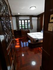 Wood-paneled bedroom with large window and polished wooden floor