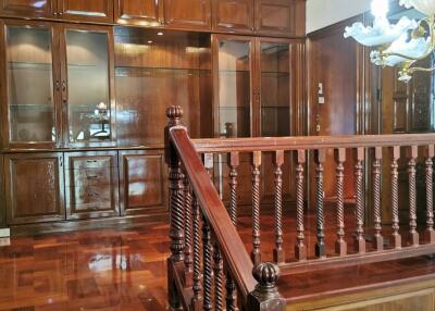 Wooden staircase with ornate handrail and overhead lighting fixtures