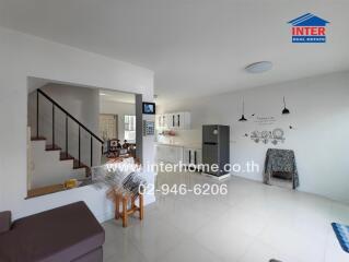 A modern living room and kitchen area with white walls and tile flooring