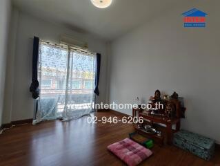 Spacious living room with hardwood flooring, large window with balcony access, and minimalist decor