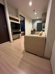 Living room with beige sofa and TV unit, view towards dining area