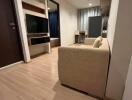 Living room with beige sofa and TV unit, view towards dining area