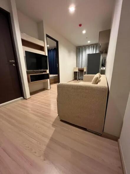 Living room with beige sofa and TV unit, view towards dining area