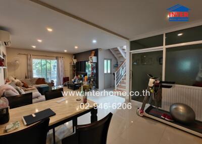 Spacious and well-lit living area with dining table and exercise equipment