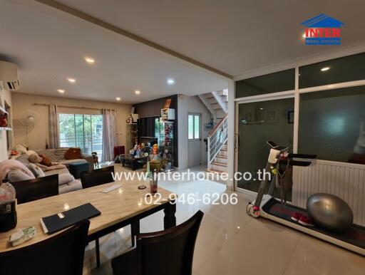 Spacious and well-lit living area with dining table and exercise equipment