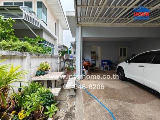 Exterior view of a building with a carport and garden area.