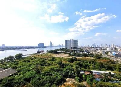 Panoramic view of the city and river with high-rise buildings, greenery, and a clear blue sky