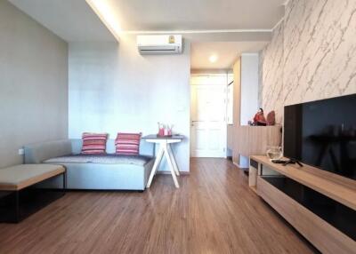 Modern living room with wood flooring, wall-mounted air conditioner, sofa, and TV unit