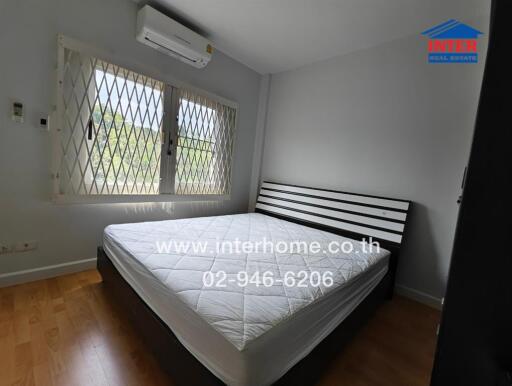 Bedroom with bed, window with grill, and air conditioner