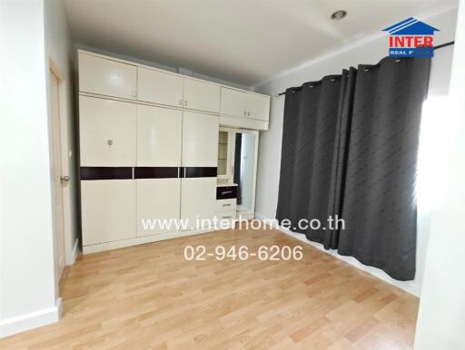 Spacious bedroom with large wardrobe and wooden flooring