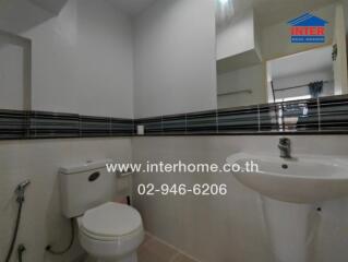 Bathroom with toilet, sink, mirror, and wall tiles