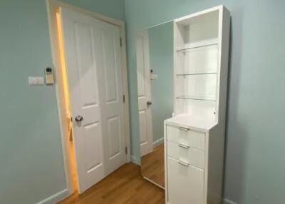 Bedroom with wooden flooring, white door, and a white shelf unit