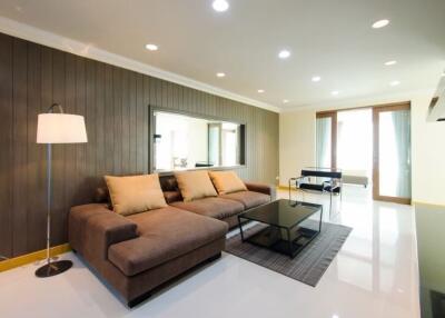 Modern living room with brown sofa, coffee table, floor lamp, and large mirror on the wall