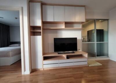 Living room with built-in entertainment center and view of adjacent bedroom and kitchen