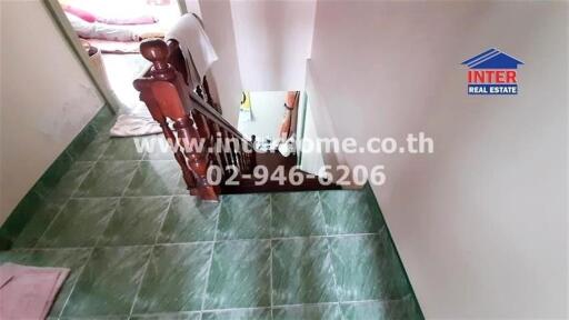 Image of a stairway with green-tiled flooring and wooden railing.