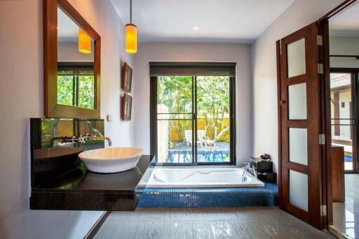 Modern bathroom with a large window, bathtub, and stylish sink.