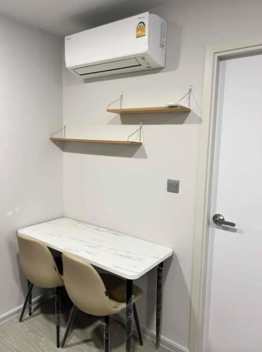 Small study corner with table, chairs, wall shelves, and air conditioner