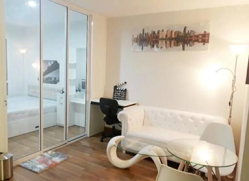 Modern living area with a white couch, glass table, and wall art