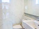 Modern white-tiled bathroom with enclosed toilet, sink, large mirror and window