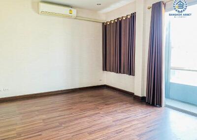 Empty living room with wooden floor and large window with curtains