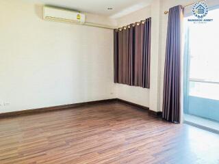 Empty living room with wooden floor and large window with curtains