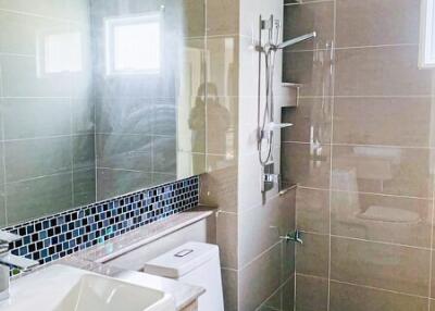 Modern bathroom with tiled walls, wall-mounted shower, and large mirror