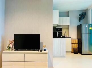 living area with TV and view of a modern kitchen