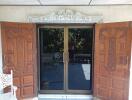 Double wooden doors with intricate carvings opening to a balcony with glass doors