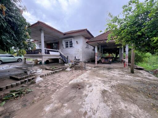 Exterior view of a single-story house with a covered porch and surrounding greenery