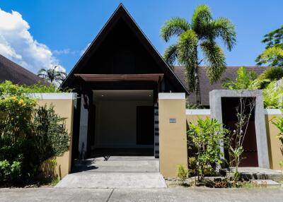 Exterior view of a modern house with a triangular roof and lush greenery