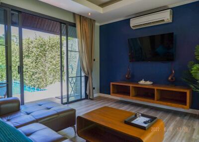 Modern living room with a leather couch, wall-mounted TV, and sliding glass doors