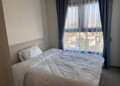 A cozy bedroom with a large window and white bedding