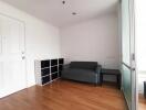 small living room with wooden floor, couch, storage unit, and glass sliding door