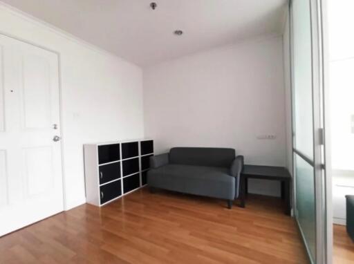 small living room with wooden floor, couch, storage unit, and glass sliding door