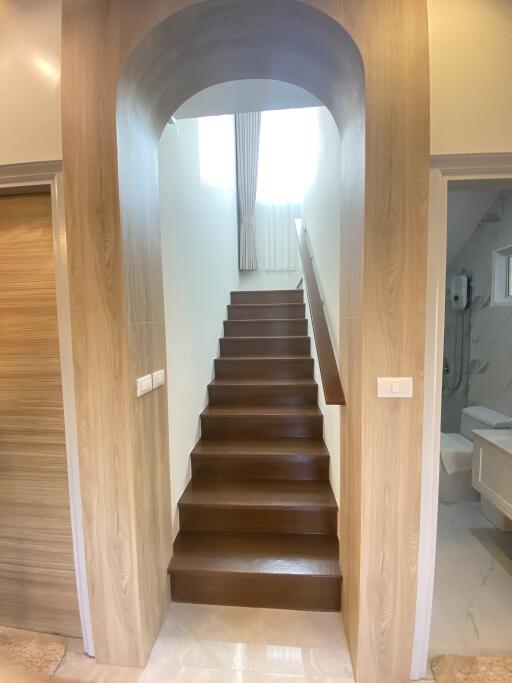 Staircase leading to an upper level with wooden steps, arched entryway, and a bathroom visible on the right.