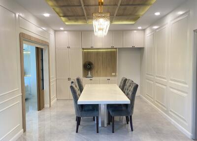 Elegant dining area with cushioned chairs, chandelier, and built-in cabinetry