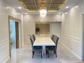 Elegant dining area with cushioned chairs, chandelier, and built-in cabinetry