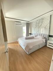 Bedroom with large bed, marble accent wall, and wooden flooring