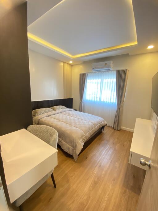 Modern bedroom with bed, desk, and natural light