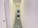 Narrow laundry room with stacked washer and dryer