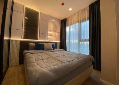 Modern bedroom with large bed, built-in shelves, and floor-to-ceiling window with curtains