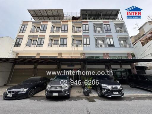 Front view of a multi-story residential building with parked cars