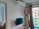 Living room with TV, air conditioner, and shelving unit