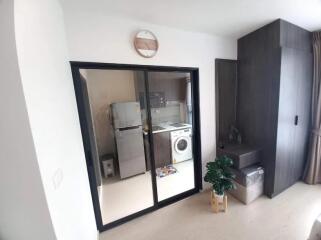 Modern laundry area with a washing machine, refrigerator, and storage space.