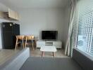 Modern living room with a TV, dining table, and large window