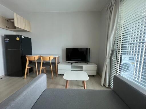 Modern living room with a TV, dining table, and large window