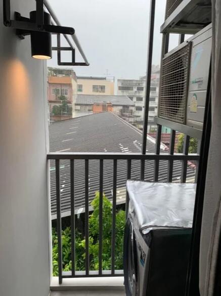 Small balcony with a washing machine and railing.