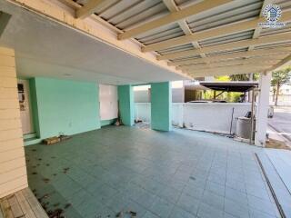 View of an outdoor covered space with tiled floor and some greenery