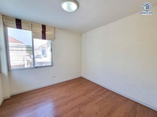 Empty bedroom with large window and wooden flooring